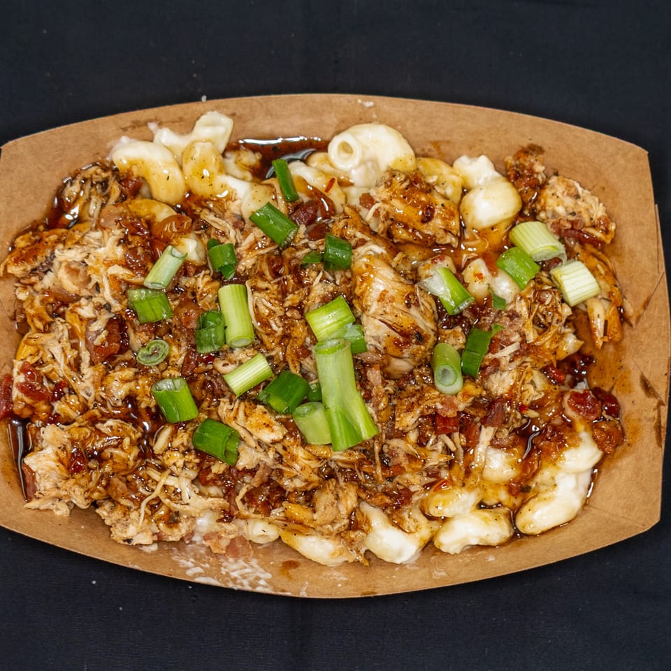 Jackpot's BBQ pulled chicken mac and cheese with green onions in a brown paper tray.