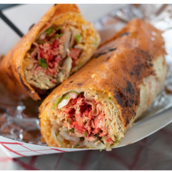 Two halves of a Jackpot burrito, revealing seasoned chicken, red sauce, and fresh vegetables.