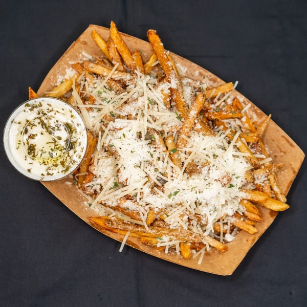 Golden fries topped with grated Parmesan cheese and parsley, with a side of creamy dipping sauce.