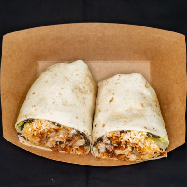 Two Jackpot burritos, cut in half, revealing rice, cheese, and meat, in a brown paper tray.