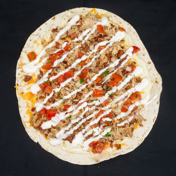 Jackpot's flatbread pizza with shredded chicken, diced tomatoes, and a white sauce drizzle.